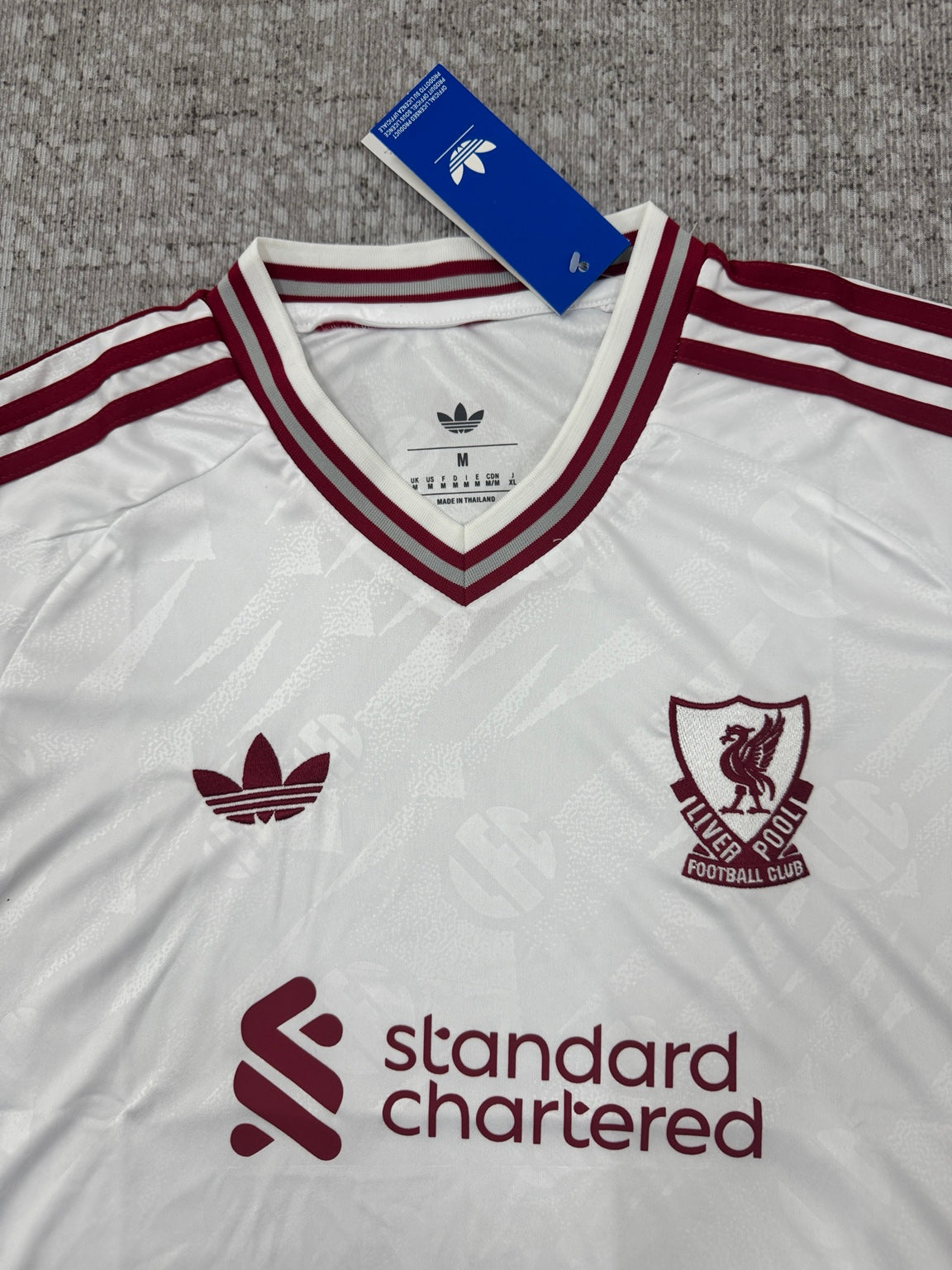Détail col et écusson maillot Liverpool blanc et bordeaux
