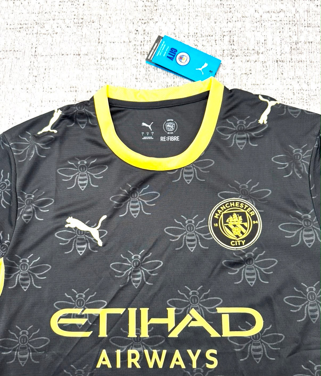Détail écusson, motifs abeilles et sponsor du maillot extérieur Manchester City 2026/27