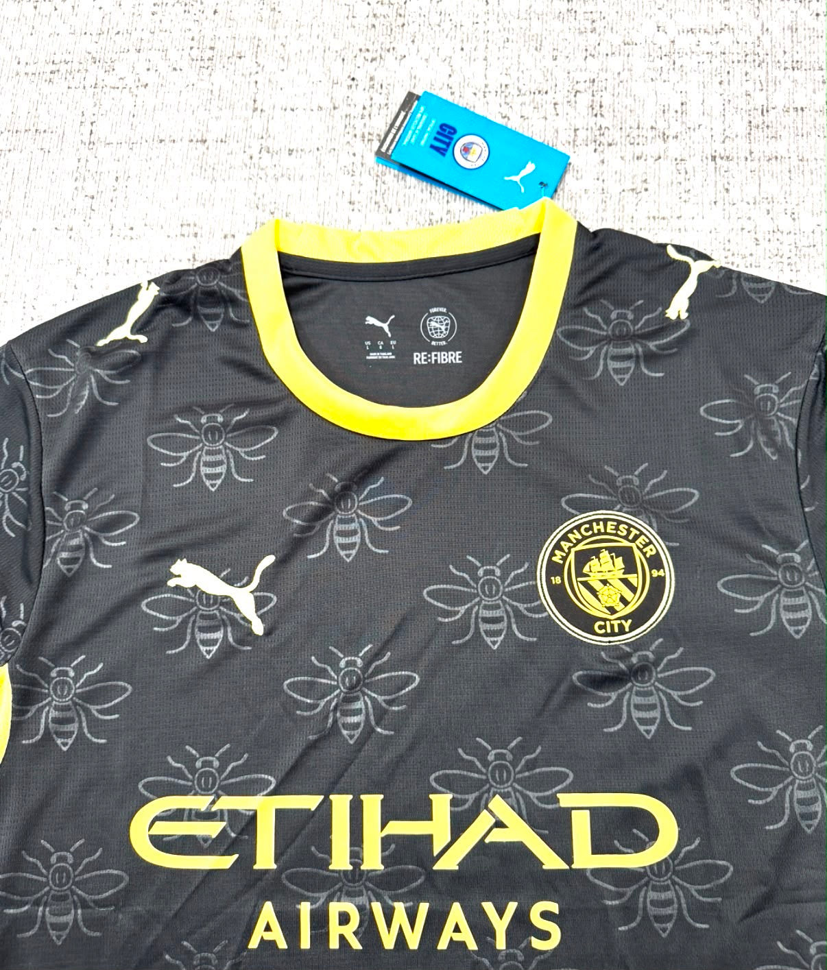 Détail écusson, motifs abeilles et sponsor du maillot extérieur Manchester City 2026/27